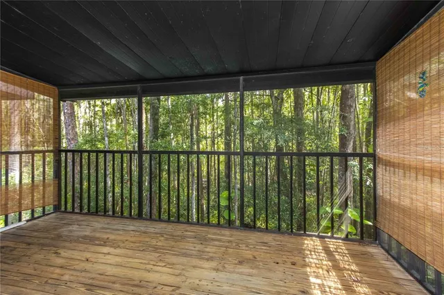 an empty room with wooden floor chandelier fan and windows