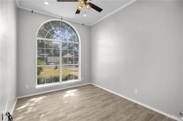 an empty room with wooden floor fan and windows