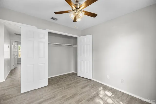 an empty room with wooden floor and a ceiling fan