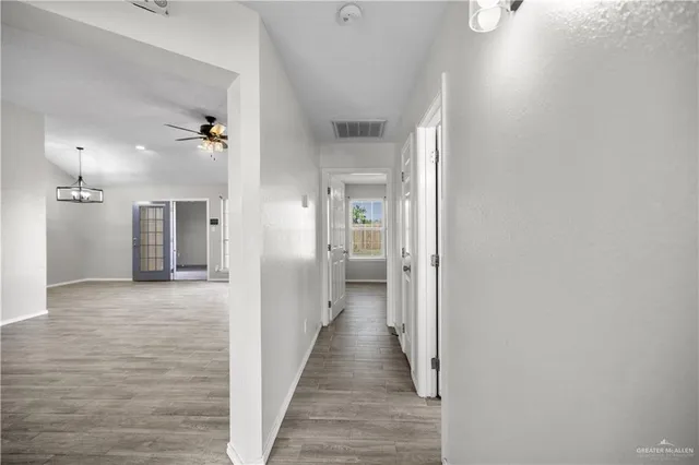 a view of a hallway with wooden floor and a bathroom