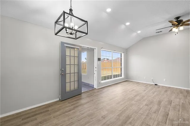 an empty room with wooden floor fan and windows