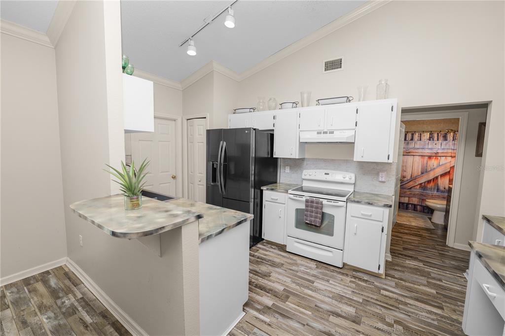 225 Lindale Street Lakeland, FL 33809 - Photo 15 of 37 a kitchen with stainless steel appliances a refrigerator a stove a sink and white cabinets