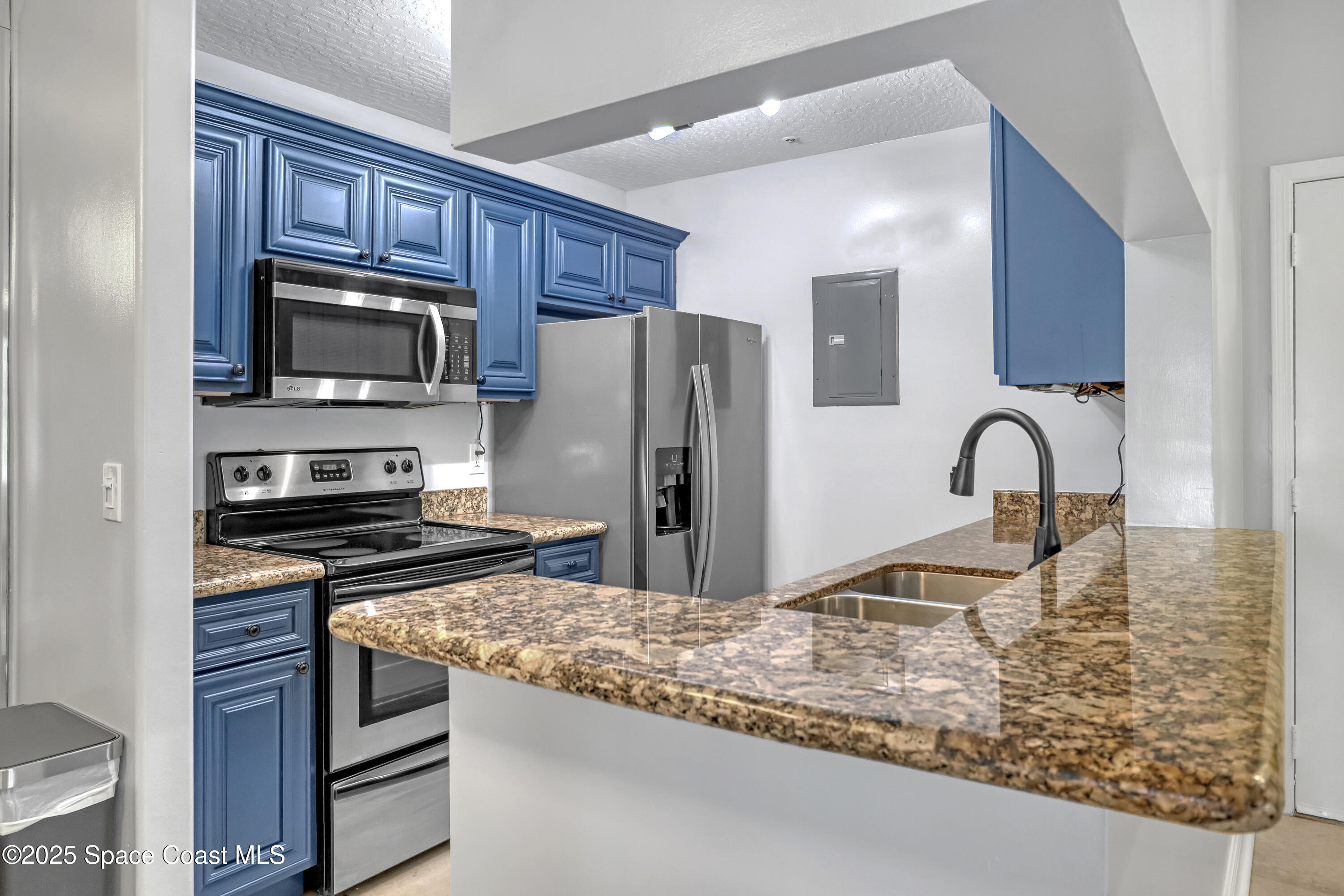 7667 North Wickham Road, Unit 224 Melbourne, FL 32940 - Photo 14 of 32 a kitchen with stainless steel appliances granite countertop a stove refrigerator and microwave
