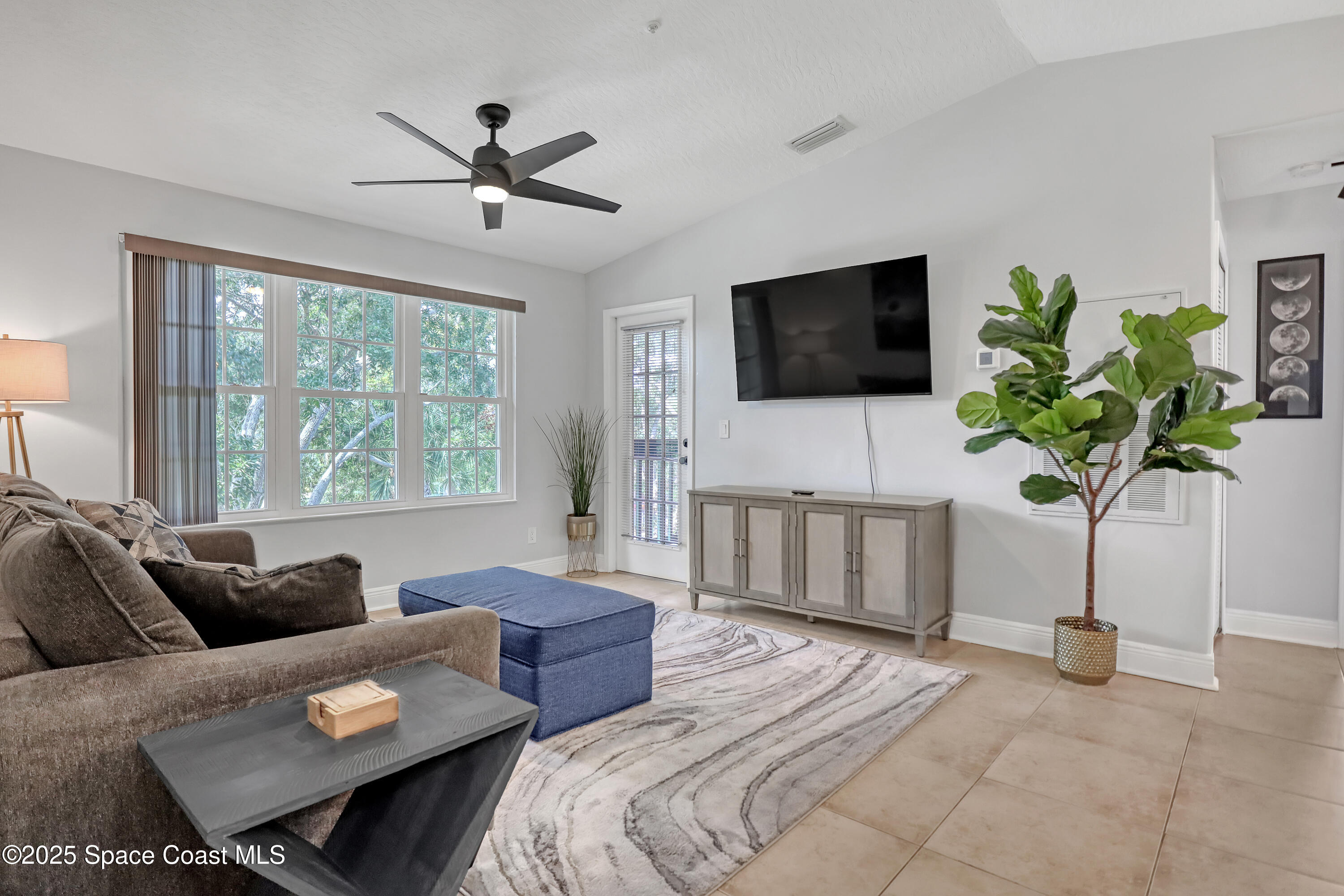 7667 North Wickham Road, Unit 224 Melbourne, FL 32940 - Photo 7 of 32 a living room with furniture a flat screen tv and a large window