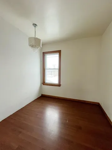 an empty room with wooden floor chandelier and window