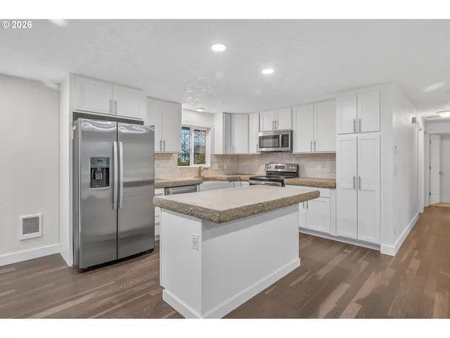 a kitchen with stainless steel appliances granite countertop a refrigerator and a stove top oven