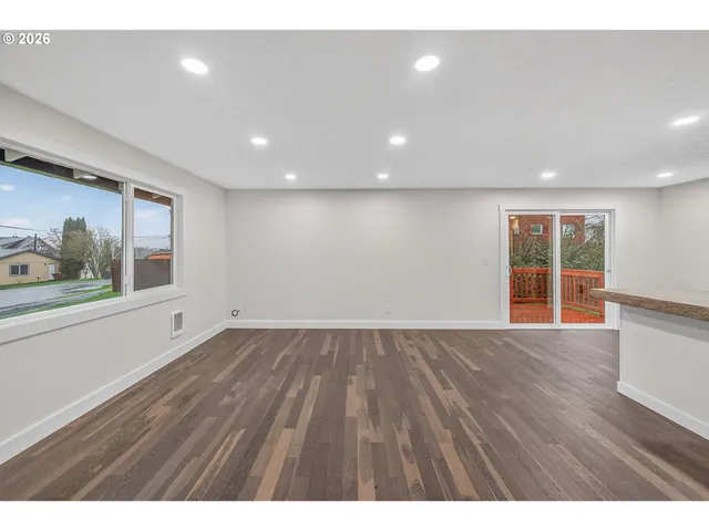 a view of an empty room with wooden floor and windows