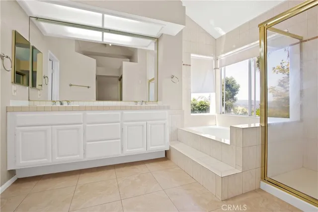 a bathroom with a bathtub a sink a vanity and a large mirror