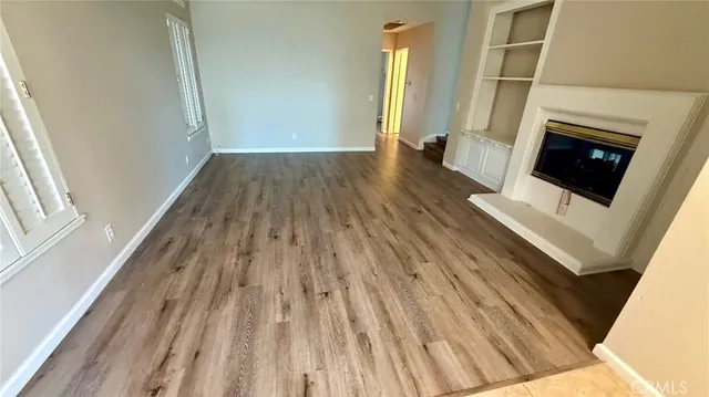 a view of a livingroom with wooden floor and a fireplace