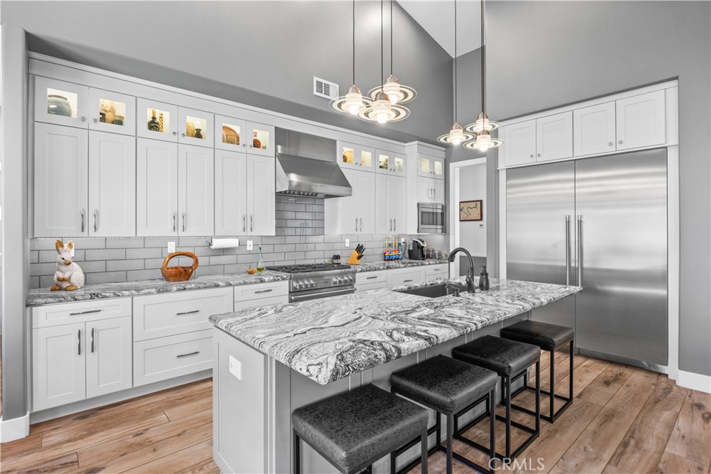 27300 Stirrup Way Tehachapi, CA 93561 - Photo 13 of 45 a kitchen with granite countertop a stove a sink dishwasher a refrigerator with white cabinets and wooden floor