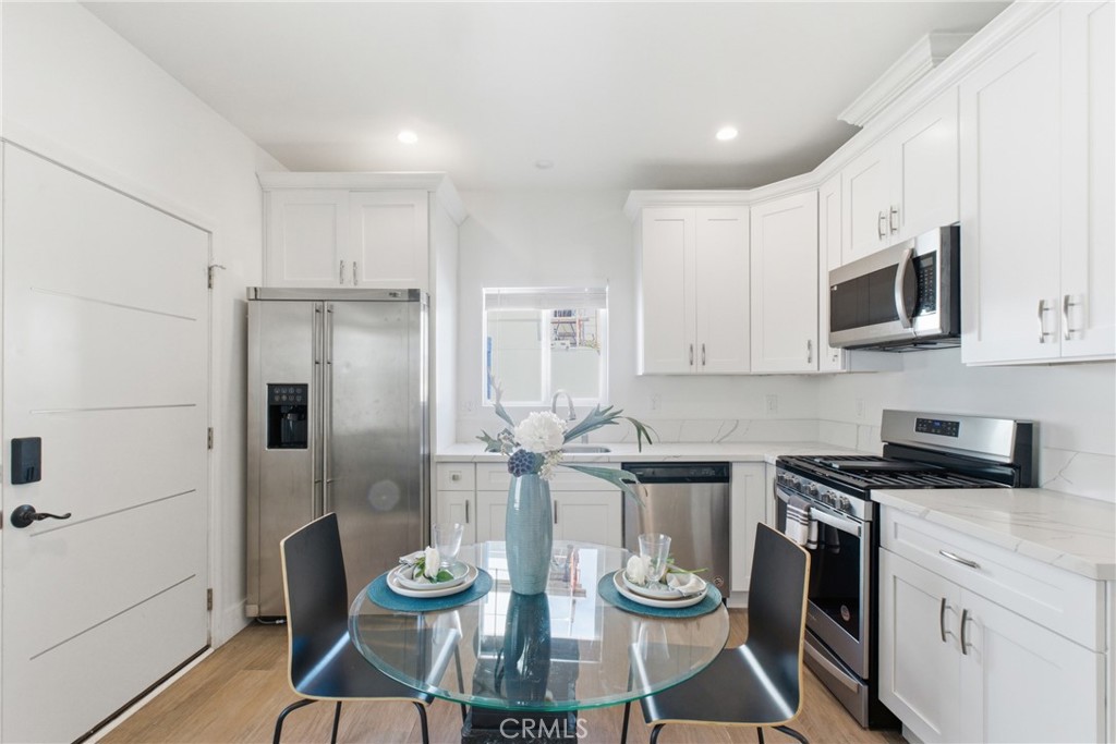1364 Ridgeley Drive Los Angeles, CA 90019 - Photo 20 of 25 a kitchen with stainless steel appliances kitchen island granite countertop a refrigerator a stove a microwave oven a sink with island and chairs