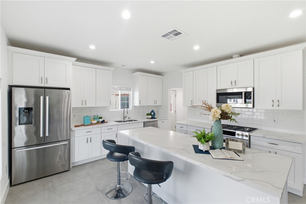 1364 Ridgeley Drive Los Angeles, CA 90019 - Photo 6 of 25 a kitchen with white cabinets and stainless steel appliances