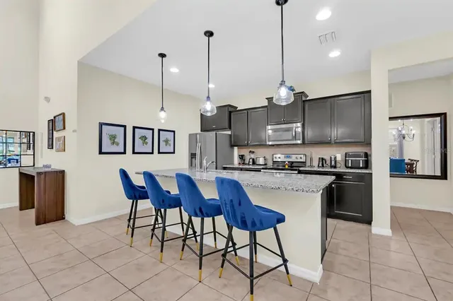 a kitchen with stainless steel appliances granite countertop a stove a sink a microwave a refrigerator with a dining table and chairs