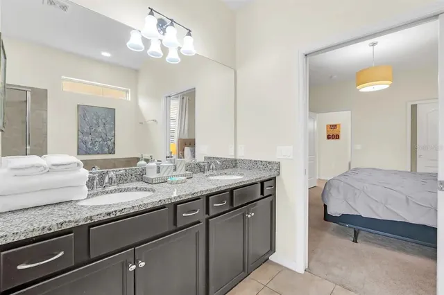 a en suite bathroom with a granite countertop double vanity sink and a mirror