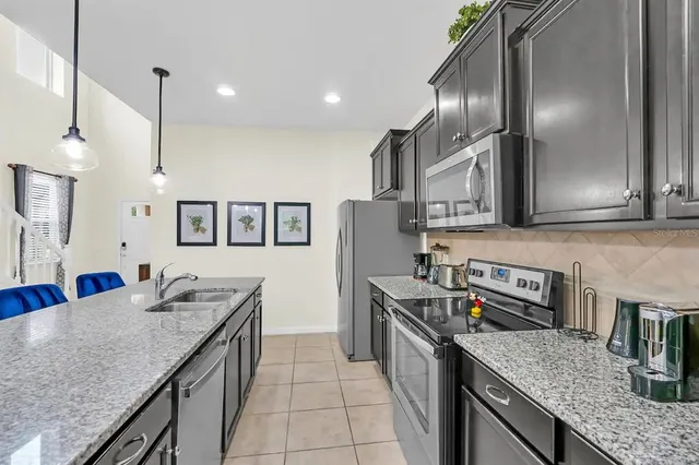 a kitchen with stainless steel appliances granite countertop a sink a stove and a wooden floors