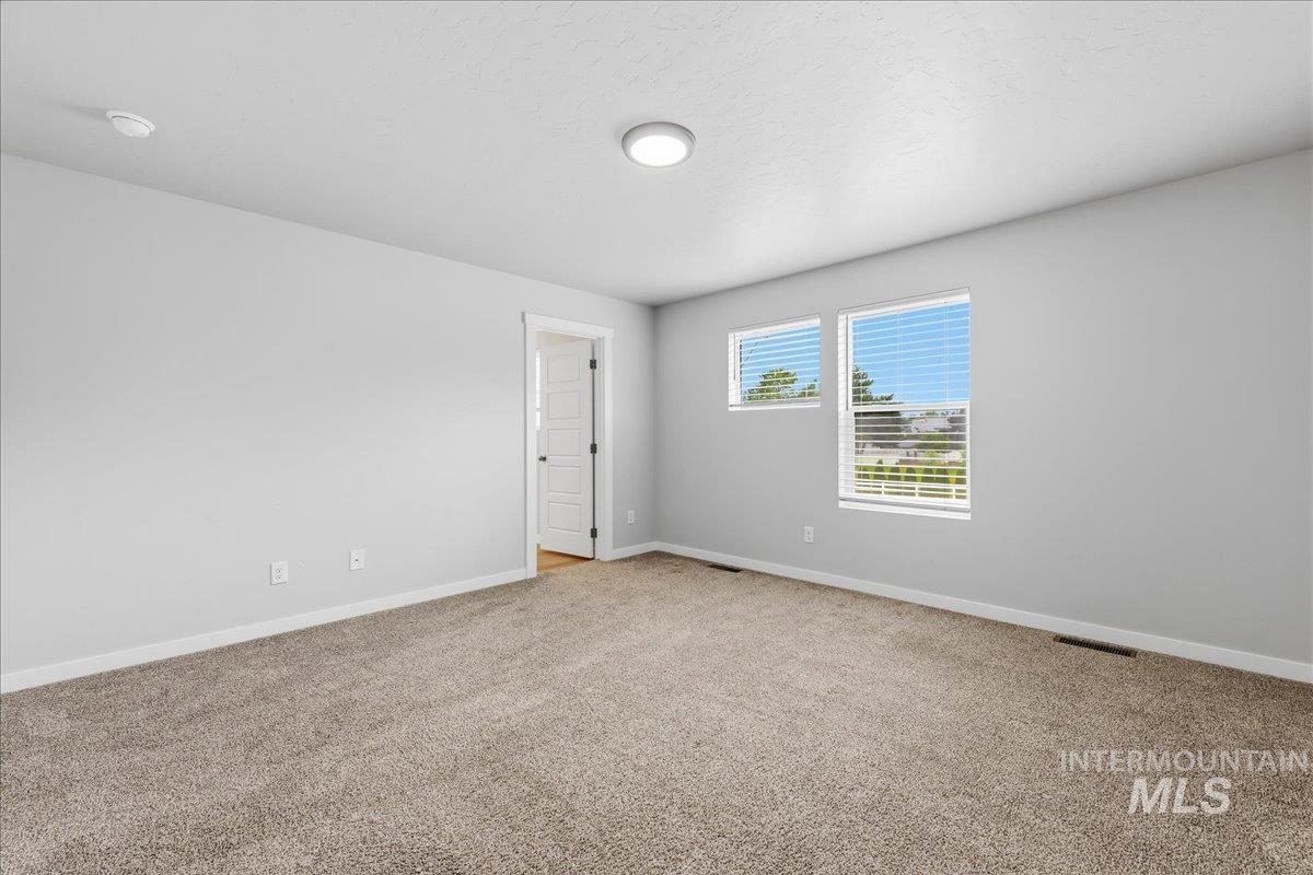 12475 West Victory Road Boise, ID 83709 - Photo 16 of 26 Spacious room featuring neutral carpeting, light gray wall paint, and white trim
