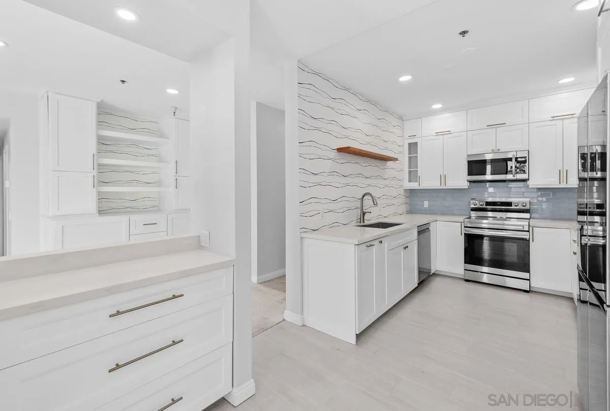 5845 Friars Road, Unit 1201 San Diego, CA 92110 - Photo 5 of 24 a kitchen with kitchen island a white cabinets and stainless steel appliances