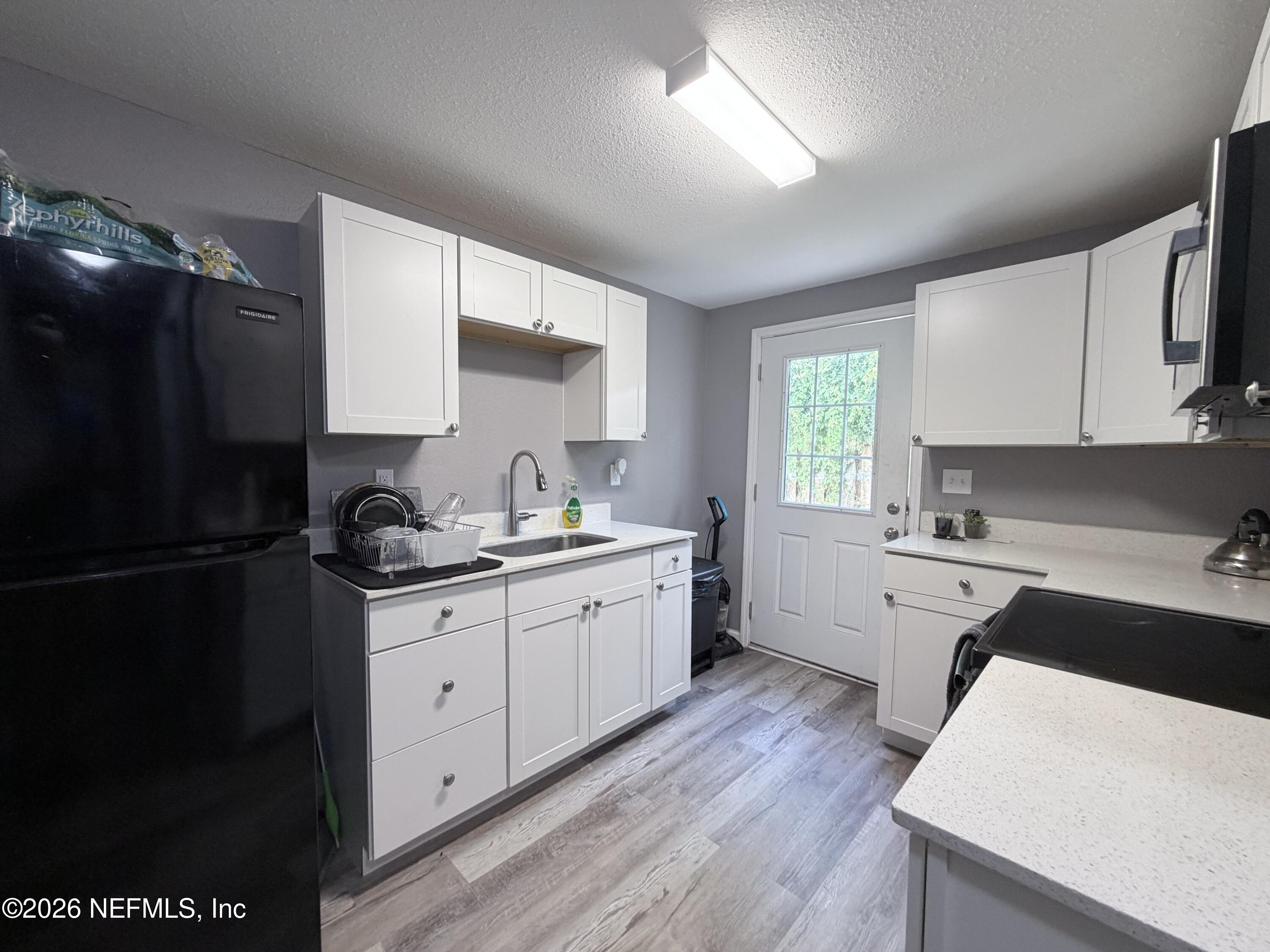 5336 Cruz Road Jacksonville, FL 32207 - Photo 26 of 29 a kitchen with a sink a refrigerator a stove and cabinets
