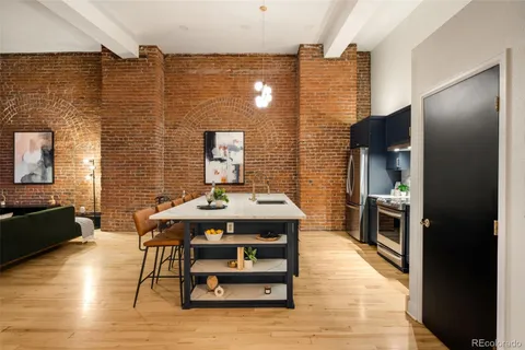 a dining room with stainless steel appliances kitchen island granite countertop a table chairs and a refrigerator