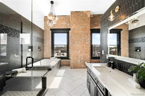 a spacious bathroom with a granite countertop double vanity sink a bathtub and window