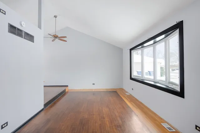 a view of empty room with wooden floor and fan