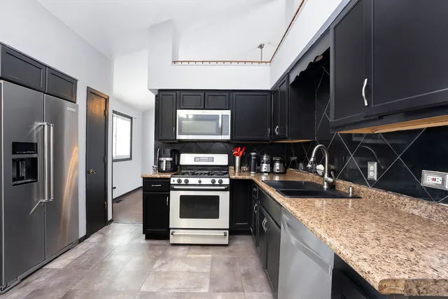 a kitchen with stainless steel appliances granite countertop a sink stove and refrigerator