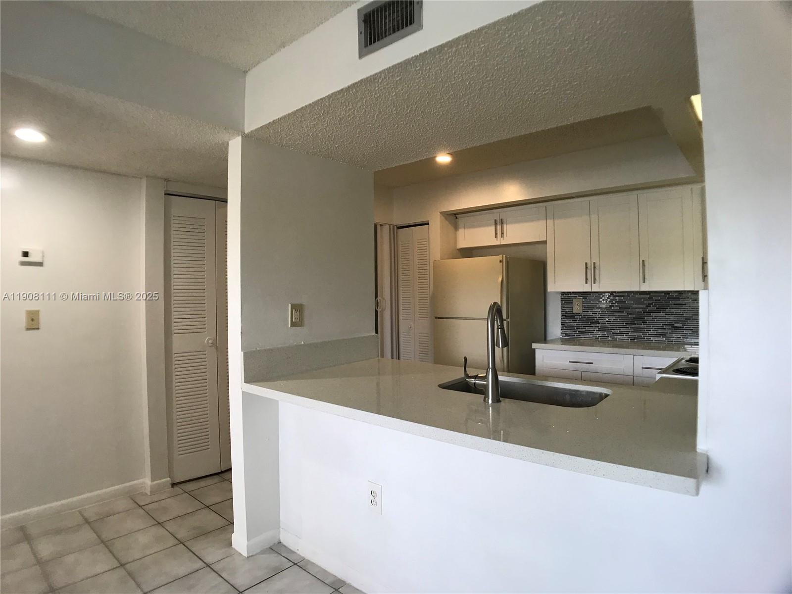 8590 Southwest 212th Street, Unit 211 Cutler Bay, FL 33189 - Photo 5 of 22 a kitchen with kitchen island a counter top space and a refrigerator