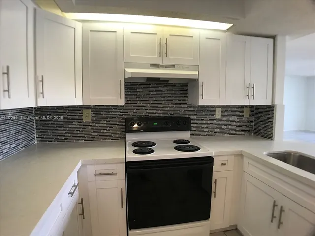 a kitchen with granite countertop a stove sink and cabinets