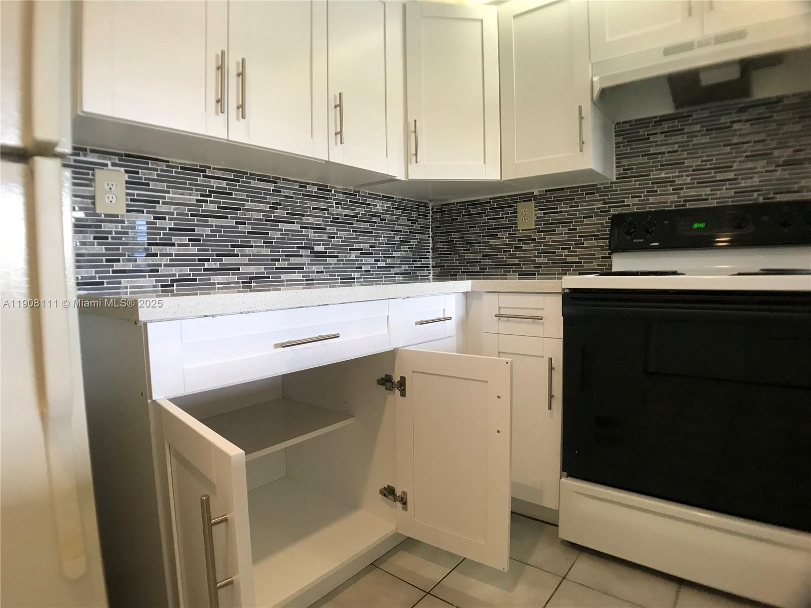 8590 Southwest 212th Street, Unit 211 Cutler Bay, FL 33189 - Photo 9 of 22 a kitchen with granite countertop white cabinets and white appliances