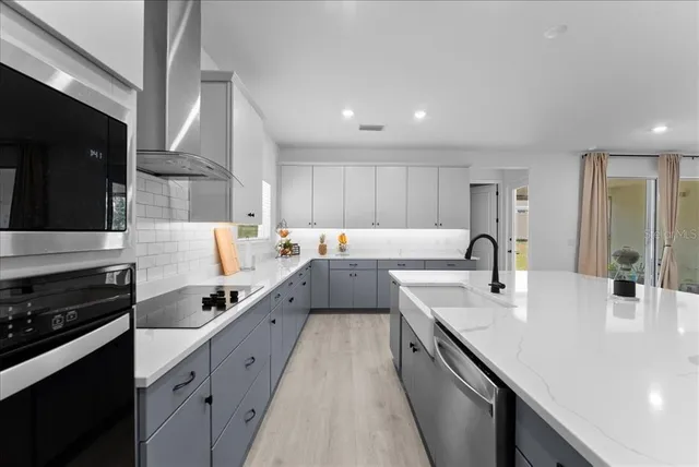 a large kitchen with stainless steel appliances sink a stove and cabinets