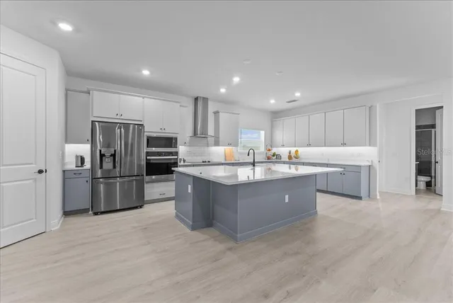 a large kitchen with kitchen island a large counter top stainless steel appliances and cabinets