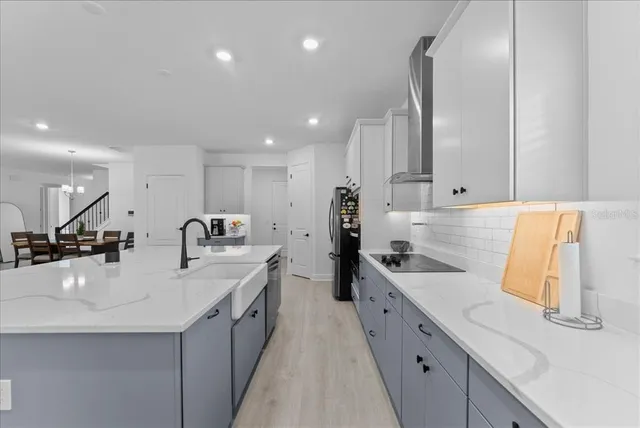 a large white kitchen with a sink and dishwasher a stove top oven with wooden floor