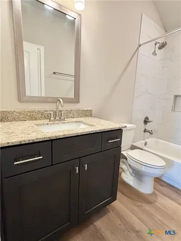 a bathroom with a granite countertop toilet sink and mirror