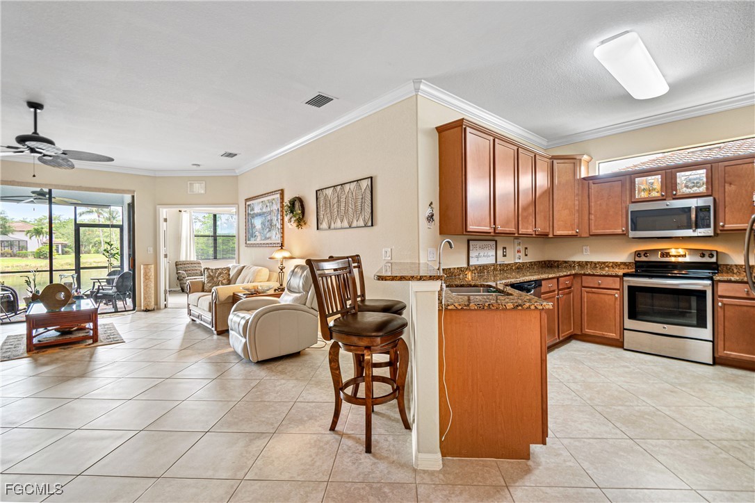 9138 Water Tupelo Road Fort Myers, FL 33912 - Photo 12 of 28 a kitchen with stainless steel appliances granite countertop a stove top oven a sink dishwasher a dining table and chairs with the view of kitchen
