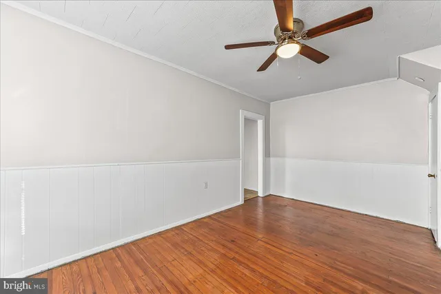an empty room with wooden floor fan and windows