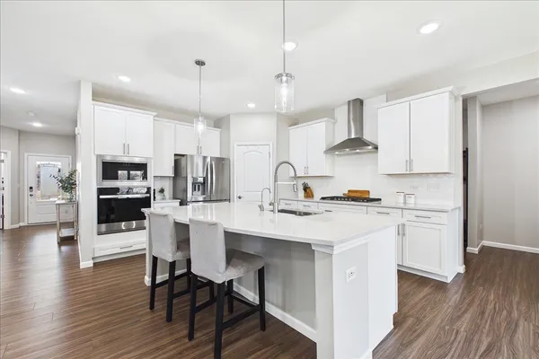 a kitchen with stainless steel appliances kitchen island granite countertop a table chairs refrigerator and microwave