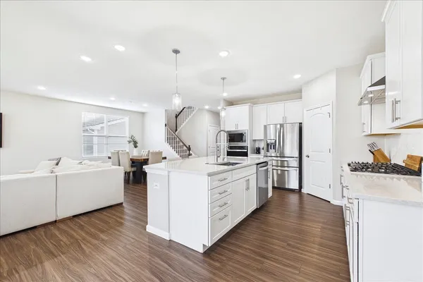 a kitchen with cabinets wooden floor and stainless steel appliances