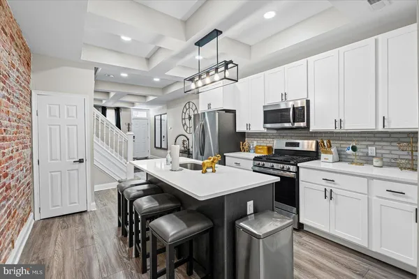 a kitchen with stainless steel appliances a stove a sink dishwasher a microwave oven a stove with white cabinets and wooden floor