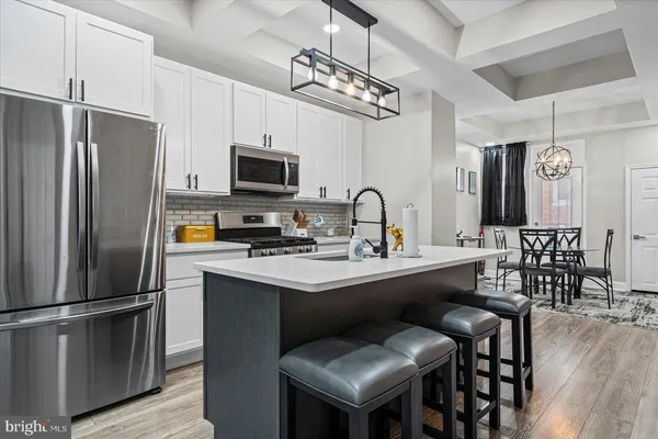 a kitchen with stainless steel appliances a sink a stove a refrigerator cabinets and a dining table