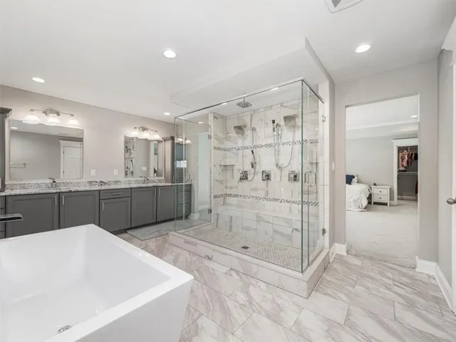 a bathroom with a tub a mirror and a shower