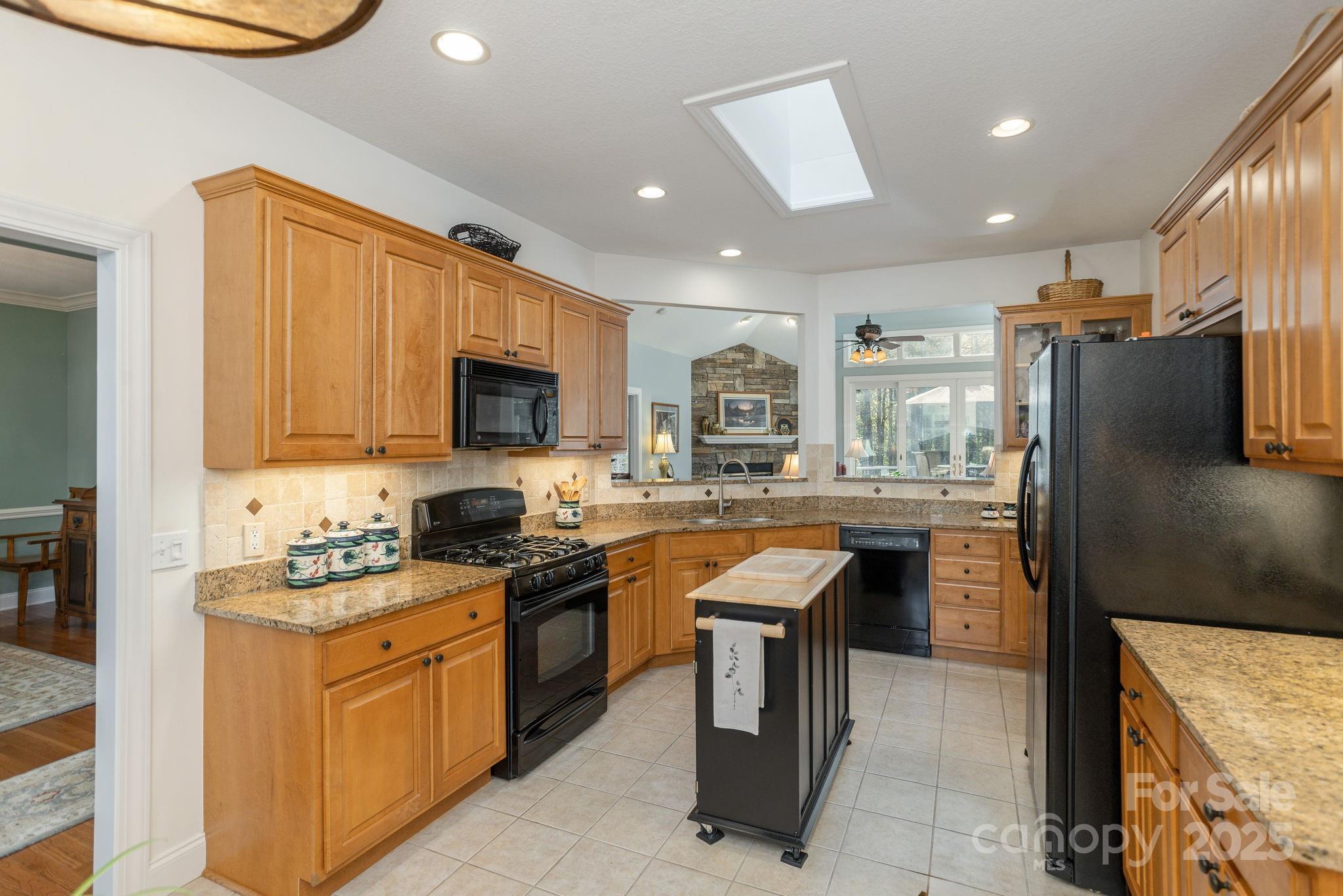 115 Chancery Court Flat Rock, NC 28731 - Photo 16 of 47 a kitchen with stainless steel appliances granite countertop a stove top oven a sink dishwasher a refrigerator and a dining table with wooden cabinet