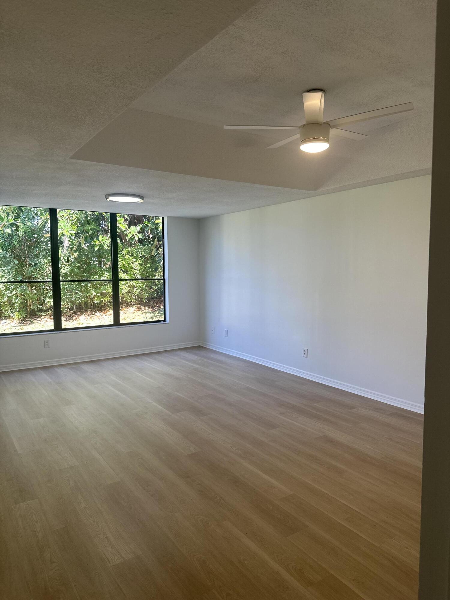 5270 Southeast Seascape Way, Unit 102 Stuart, FL 34997 - Photo 2 of 24 an empty room with wooden floor and windows