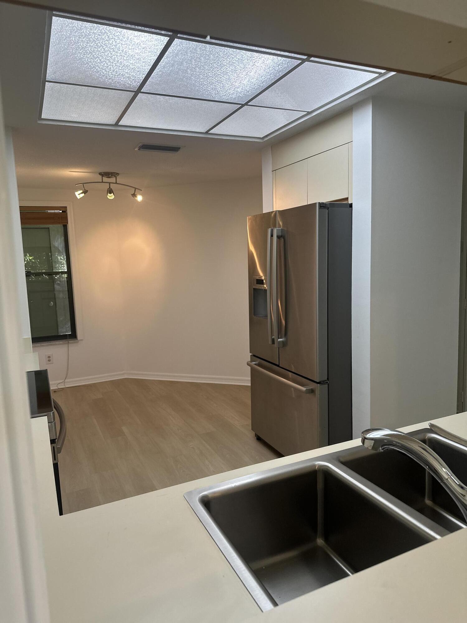 5270 Southeast Seascape Way, Unit 102 Stuart, FL 34997 - Photo 6 of 24 a kitchen with stainless steel appliances a refrigerator a sink a stove and white cabinets