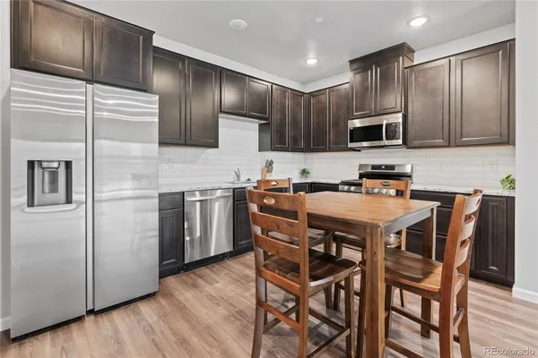 a kitchen with a table chairs refrigerator and microwave