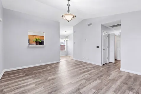 a view of an empty room with window and wooden floor