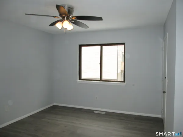 an empty room with a window and a fan