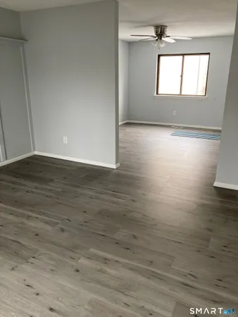 a view of empty room with wooden floor and fan