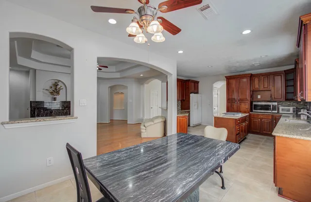 a dining room with wooden floor a chandelier fan a wooden table and chairs