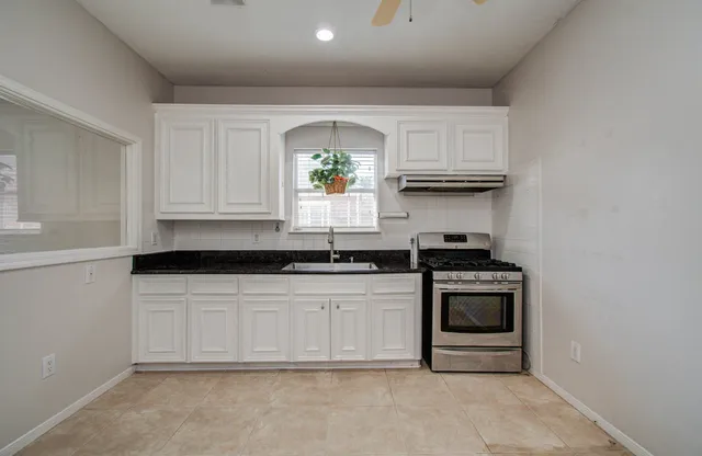 a kitchen with granite countertop a stove sink and cabinets