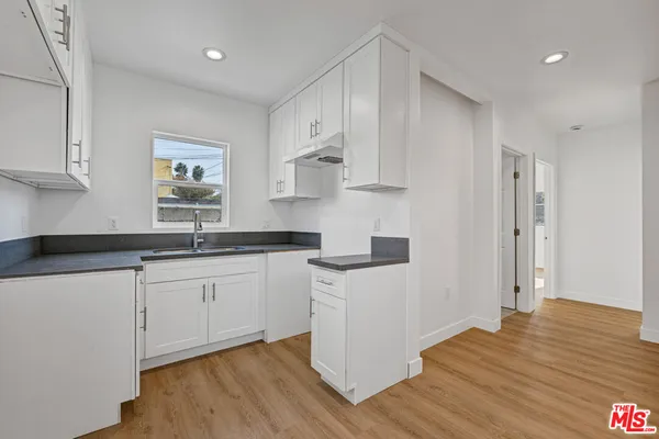 a kitchen with granite countertop white cabinets and wooden floor